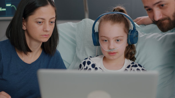 医院病房里，一家人坐在女儿身边，用笔记本电脑玩网络视频游戏图片下载