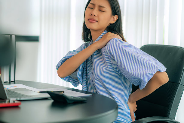 坐在椅子上的年轻女商人在办公室里背痛的特写图片下载