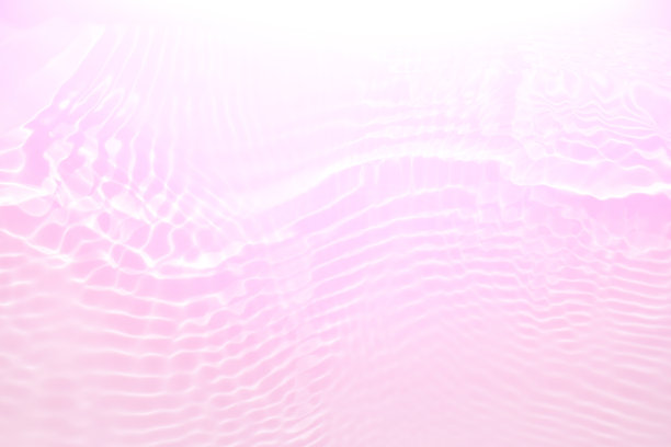 紫色的水面上泛起涟漪。散焦模糊透明粉红色透明平静水面纹理与飞溅和泡沫。水波与闪亮的图案纹理背景。图片下载