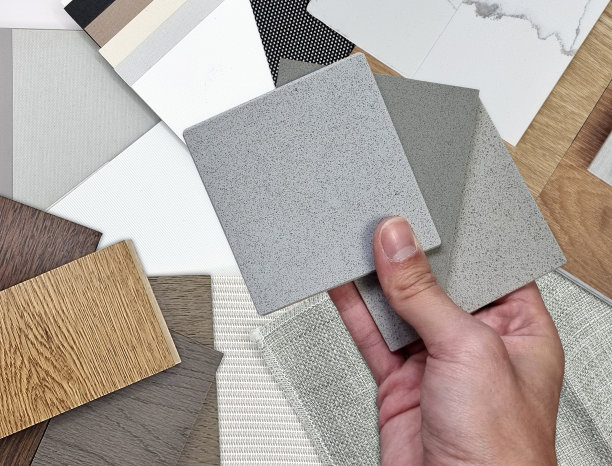 建筑师的手拿着石英石样品与帷幔织物、木质层压地板砖、乙烯基地板砖、石英石调色板样品进行比较的特写镜头。图片下载