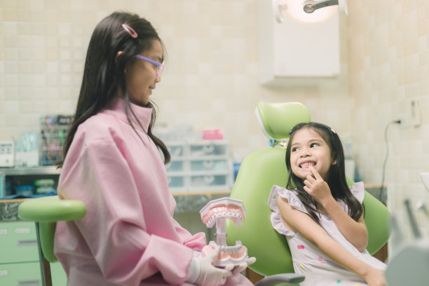 小女孩的特写镜头，她摸到一颗弯曲的乳牙，感到疼痛。牙齿脱落，牙齿问题的概念图片下载