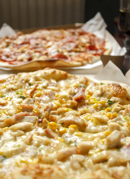 两个披萨并排躺着。垂直的照片。奶酪披萨，玉米披萨，肉披萨旁边。图片下载