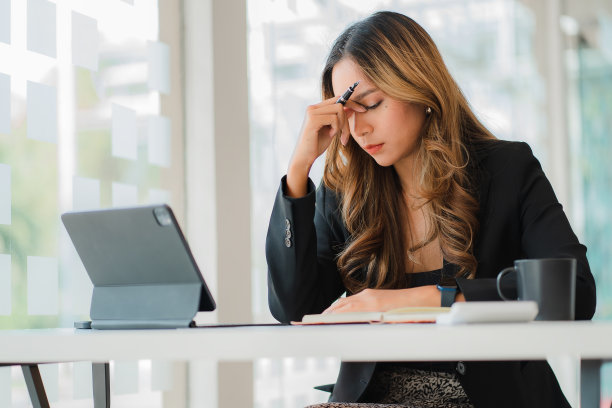 使用平板电脑工作的亚洲商界女性长时间盯着屏幕导致眼睛疲劳图片下载