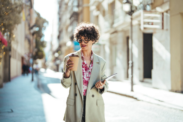 年轻漂亮的女商人拿着一次性咖啡杯图片下载