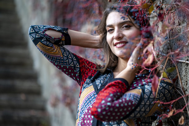 迷人的女人在秋天的背景下摆姿势拍照。图片下载