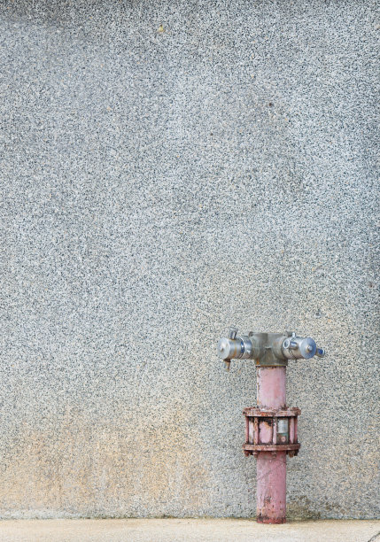 消防水带点安装在灰泥点状墙面上。管道外观颜色暗淡、陈旧。表示使用寿命较长。轻微生锈的图片下载