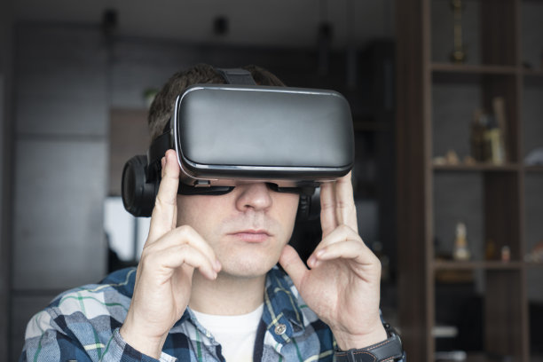 快乐的年轻英俊男子肖像，积极微笑的家伙使用，戴着现代设备虚拟现实头戴式面具或3D, AR, VR眼镜。人与技术的概念。观看360度视频图片下载