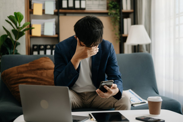 失意的年轻商人坐在家里办公的地方用笔记本电脑工作图片下载