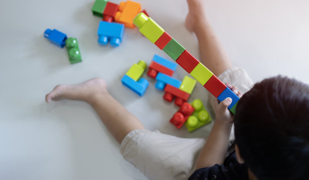 快乐的学龄前儿童玩着五颜六色的塑料玩具积木。从上面俯瞰。图片下载