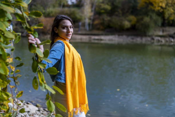 迷人的女人在秋天的背景下摆姿势拍照。图片下载