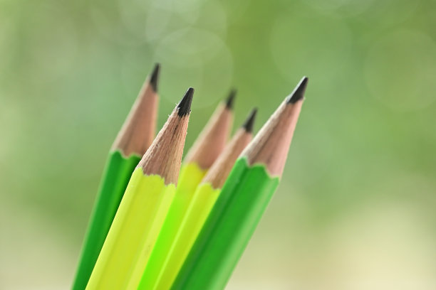 绿色和黄色的铅笔在模糊的自然背景与散景图片下载