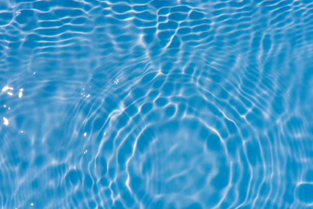 蓝蓝的水面上泛起涟漪。散焦模糊透明蓝色透明平静水面纹理与飞溅和气泡。水波与闪亮的图案纹理背景。图片下载