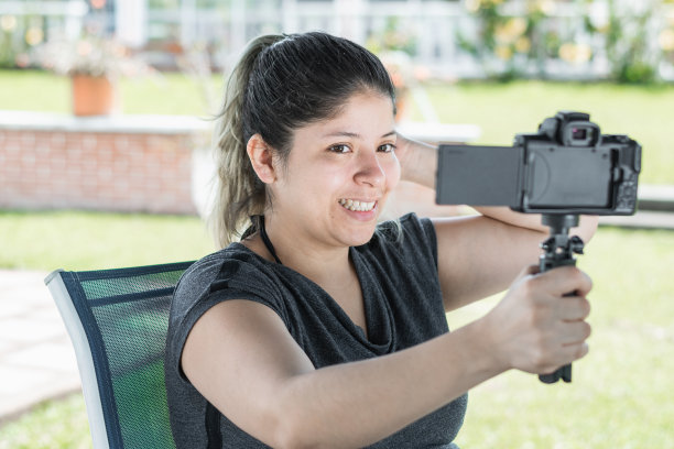 年轻的拉丁裔女博主，手拿相机拍摄自己，对着镜头微笑图片下载