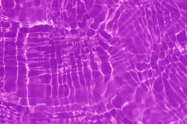 紫色的水面上泛起涟漪。散焦模糊透明粉红色透明平静水面纹理与飞溅和泡沫。水波与闪亮的图案纹理背景。图片下载