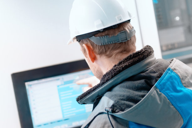 戴白色头盔的工程师将手指伸向天然气自动控制系统的触摸屏。天然气工业的现代化数字化设备。图片下载