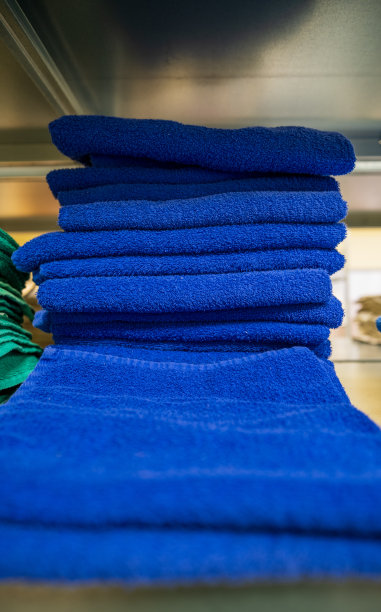 干净的蓝色毛巾，折叠，堆放在一堆。洗衣房的架子上堆放着一堆堆毛巾图片下载