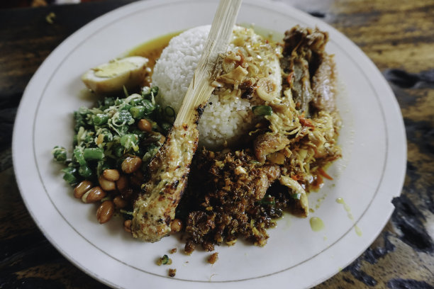 Nasi Campur Ayam Betutu用木薯叶填馅的巴厘岛烤鸡。配以蒸米饭，Sate Lilit, Jukut Antungan, Lawar Nangka和Sambal Matah。图片下载