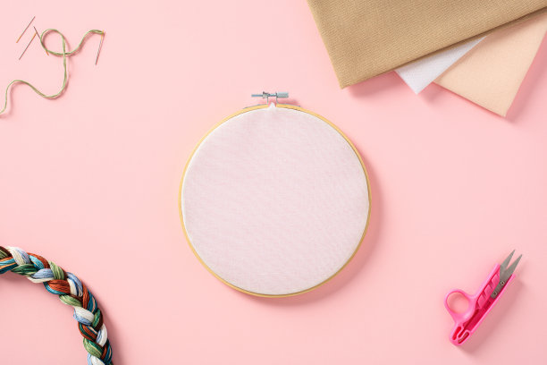 刺绣箍模型上粉红色的背景与十字绣配件。平躺，俯视图。图片下载
