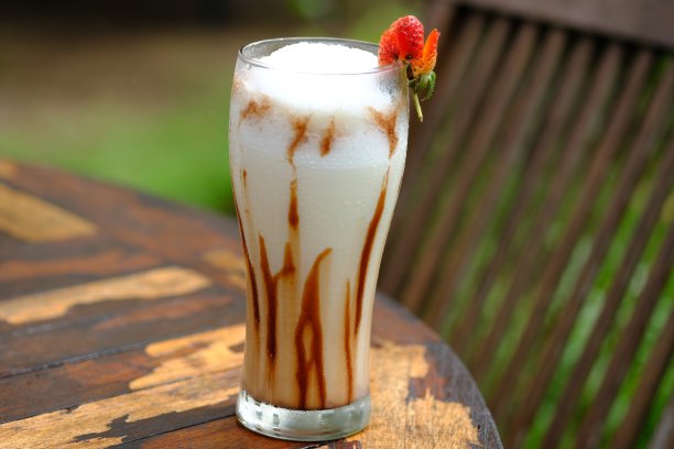 香草奶昔和融化的巧克力在一个透明的杯子里，放在木桌上。图片下载