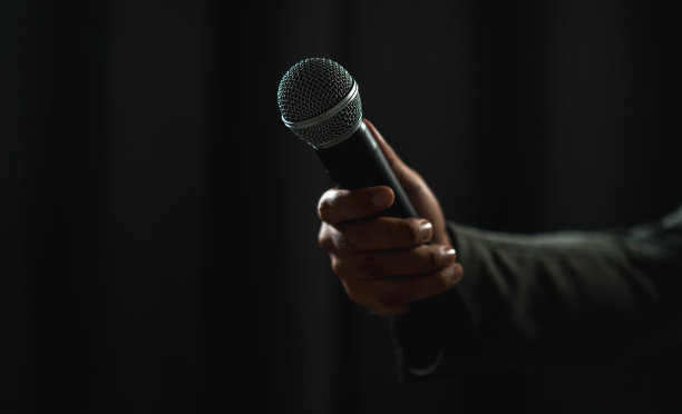 在公司商业活动中，自信成功的演说家在舞台上讲话，聚光灯照亮了黑暗。在会议大厅演讲的公众演说家。喜剧演员。图片下载