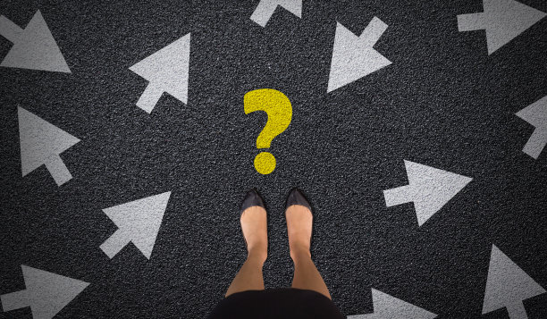 年轻的商务女士站在柏油路上，有问号和许多箭头方向。女商人的选择、决策与未来观念。俯视图图片下载