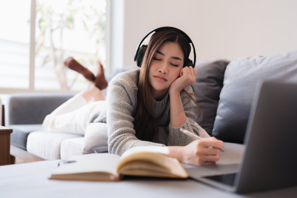 在线教育，电子学习。穿着时尚休闲服装的亚洲女性，用笔记本电脑学习，听在线课程，记笔记，在家在线学习图片下载