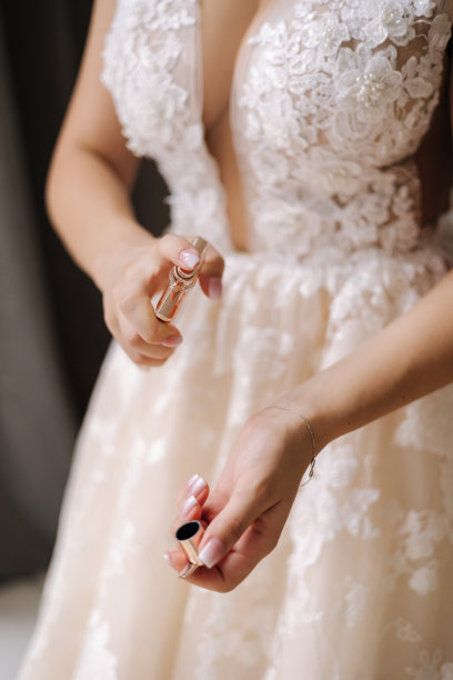 优雅的新娘在手腕上喷香水。女人用香水的特写照片。结婚的概念图片下载