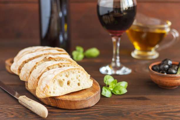 切成片的意大利面包，配红酒、橄榄油、橄榄和罗勒，木质背景。图片下载