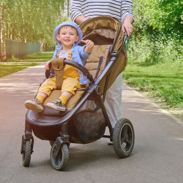 这位妇女和她的小儿子推着婴儿车散步，享受着夏日温暖的微风。2岁左右(1岁11个月)图片下载