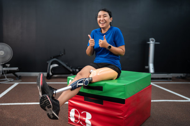 快乐的亚洲妇女与假腿锻炼在健身房或健身图片下载