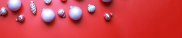 平旗把圣诞玩具放在红色的背景上。圣诞树上的粉色玩具图片下载