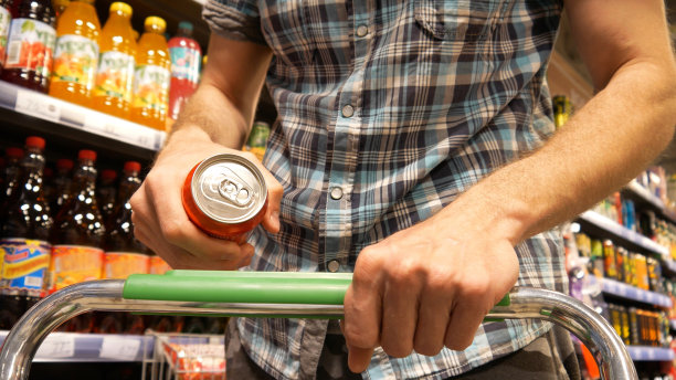 一名男性买家的特写镜头，他的手推着一辆购物车，上面放着一罐苏打水图片下载