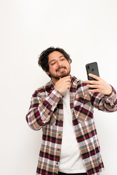 西班牙裔男子用白色背景的手机自拍的垂直图像图片下载