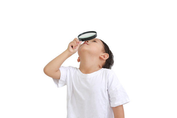 亚洲小男孩通过放大镜看孤立的白色背景。图片下载