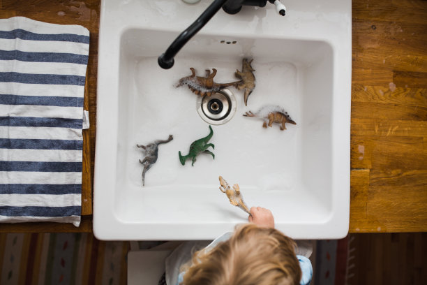 上图是小男孩的手在厨房水槽里玩玩具图片下载