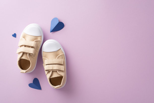 儿子向父亲致敬的温馨父亲节时刻。高角度顶视图展示幼儿的运动鞋和心形道具在紫丁香背景与空白的文字空间图片下载