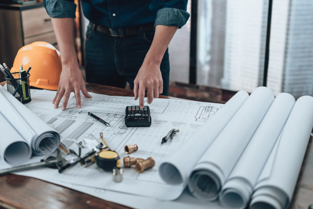 在办公室检查图纸，使用计算器，三角尺，安全眼镜，指南针，游标卡尺。工程师，建筑师，工业和工厂概念。图片下载