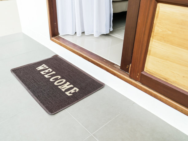 新的干净的棕色垫子，门口有“欢迎”字样。漂亮的新房子门口棕色地毯上的欢迎文字。图片下载