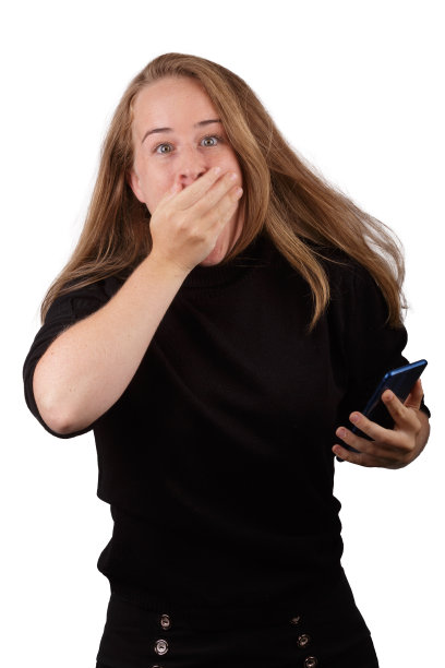 年轻的金发女孩微笑与手机在手与白色的背景。图片下载