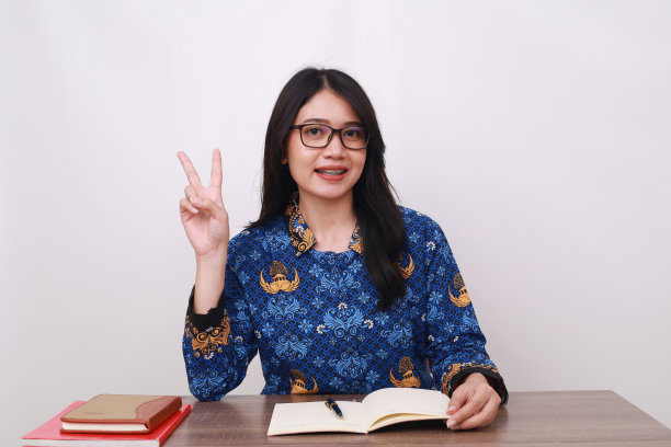 身穿印尼传统工人制服的亚洲妇女露出两根手指图片下载