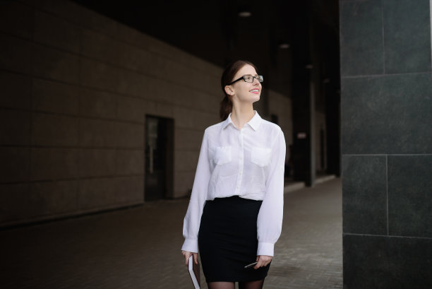 一位穿着职业装、戴着眼镜的女士带着笔记本去办公室开会图片下载