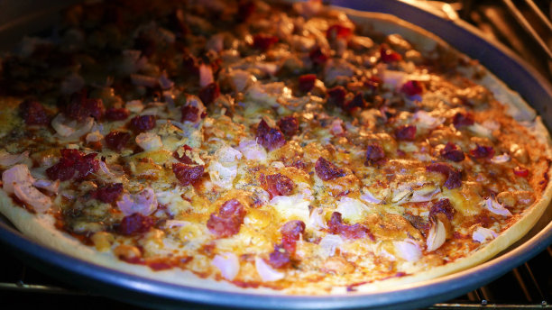 烤箱里的意大利辣香肠披萨。披萨的一天。意大利辣肠、洋葱和马苏里拉披萨配牛至图片下载