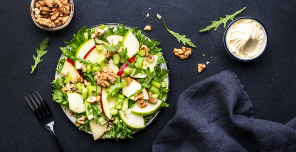 华尔道夫沙拉配红绿苹果，生芹菜，生菜，芝麻菜和核桃配蛋黄酱，黑色桌面背景，俯视图图片下载