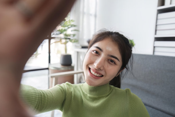 乐观的女人在家里享受空闲时间，浏览智能手机拍照图片下载