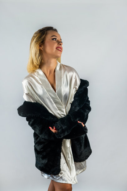 年轻漂亮的金发女郎穿着白色的丝绸长袍，上面穿了一件毛皮大衣。图片下载