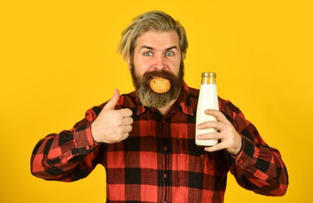 牛奶和饼干。快乐的农民吃饼干甜点。大胡子男人喝有用的牛奶和糕点。早餐或午餐吃有机农产品的健康理念图片下载