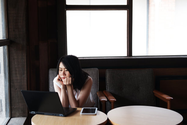 严肃的年轻亚洲女商人在办公室用笔记本电脑在线工作。她正在咖啡店上网搜索社交信息。健康和商业与科技的理念图片下载