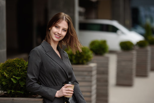 户外，一位微笑的女商人肖像。喝咖啡的漂亮女孩。图片下载