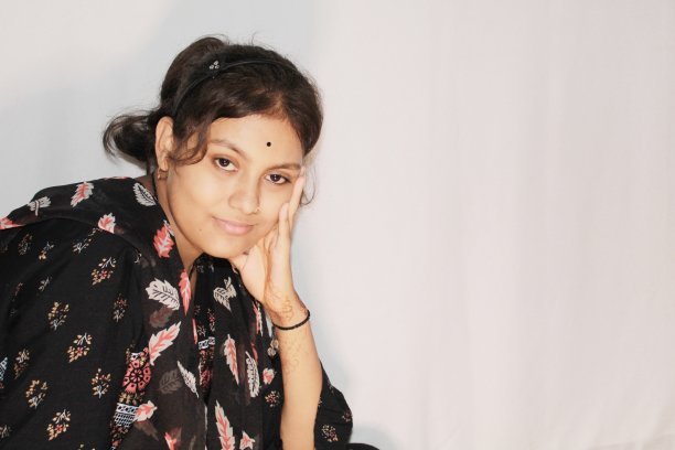 一个十几岁的印度女孩正把手放在脸颊上坐着。图片下载