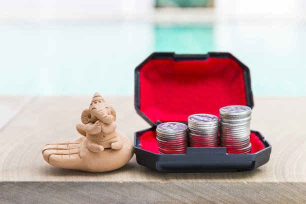 象头神泥塑与硬币堆在宝盒模糊的背景图片下载